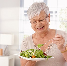 Senior woman eating salad at home