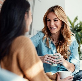 Woman smiling while drinking coffee with friend