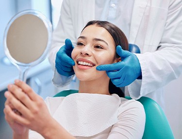 Woman smiling at reflection in handheld mirror