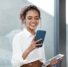 Woman smiling while looking at phone in office