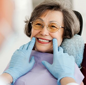Dentist with blue gloves looking at senior woman's smile