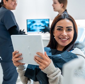 Patient smiling while holding mirror in treatment chair