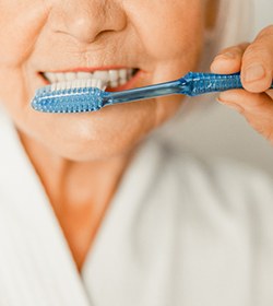 Older woman brushing her dental implants in Ridgefield