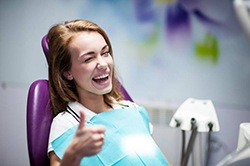 A dental patient smiling and giving a thumbs-up.