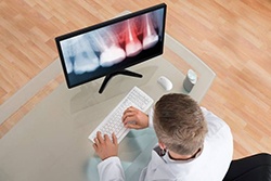 A dentist examining an X-ray on a computer.