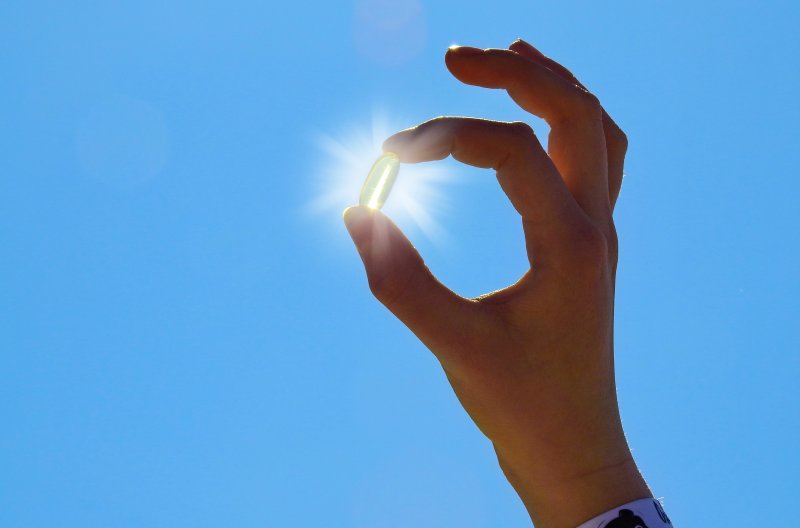 A man holding a capsule of vitamin D