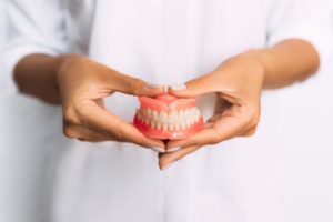 a dentist holding a pair of relined dentures